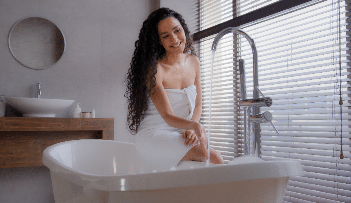 How To Extend Your Hot Water System's Lifespan - a woman running a hot bath.