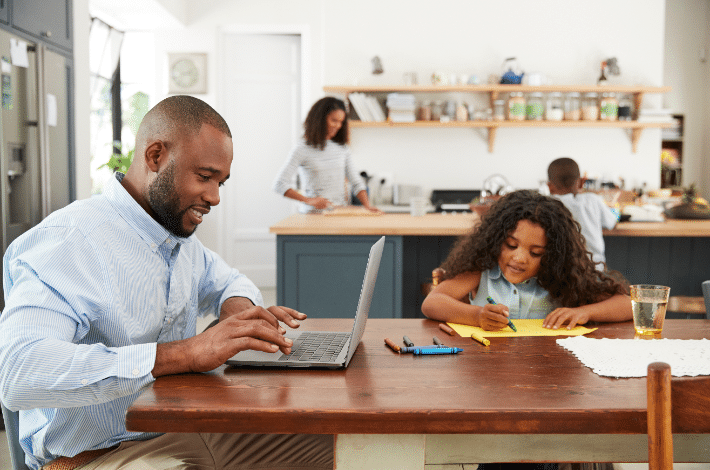 Balancing Remote Work And Parenting - dad working from him while kids are studying