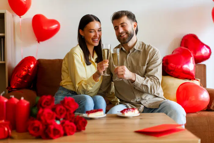 Valentine’s Day for blended families-Happy couple celebrating Valentine's Day, having romantic dinner, clinking champagne glasses and eating desserts