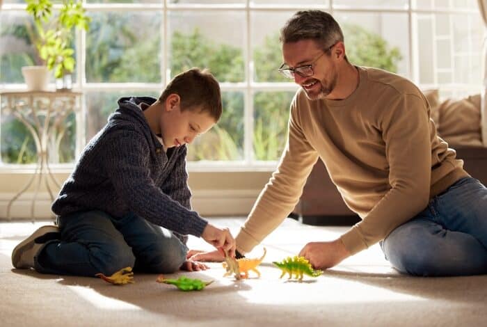 bonding with stepchildren -Stepdad and stepkid, playing with toys at house for plastic dinosaur