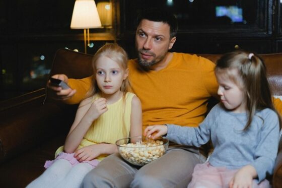 Stepdad watching TV with stepdaughters