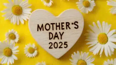 wooden heart with text "MOTHER'S DAY" and the year '2025' on a yellow background, surrounded by daisy flowers.