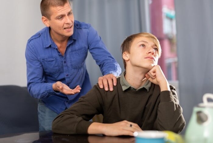 Why Do Kids Hate Their Stepparents-Young unhappy teenage boy ignoring his stepdad, man trying conversate with boy.