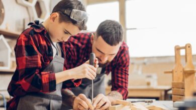 best hobbies for dads-Stepdad and stepson together at home standing at table dad holding screwdriver explaining boy working process