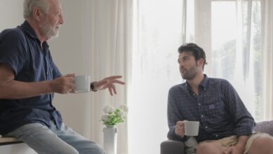 Stepparenting adult children -Stepdad drinking coffee- and talking with his stepson in a cozy living room