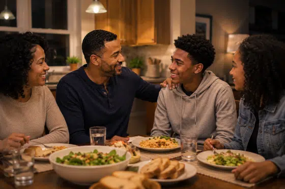Blended family laughing together during dinner while a stepdad encourages a teenage child