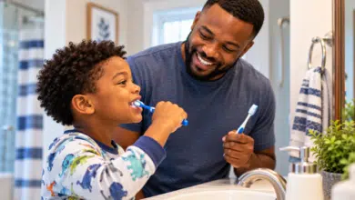 A-bathroom-scene-showing-a-stepdad-and-his-elementary-school-age-stepchild-brushing-his-teeth-in-front-of-the-mirror
