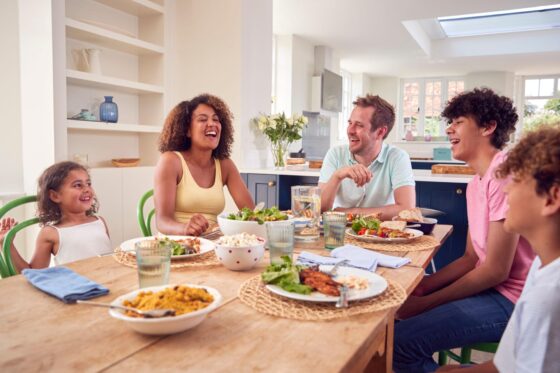 Family Sitting Around Table At Home Eating Meal Together