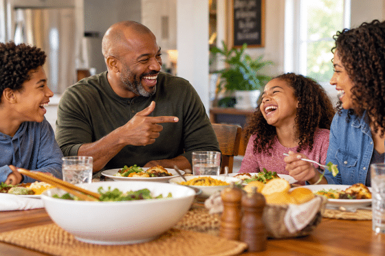 World Smile Day - A blended family sitting around the dinner table, caught in a genuine moment of laughter