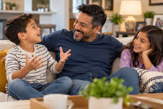 World Smile Day - Concept: A stepdad and an elementary-school-age child sitting together on a couch